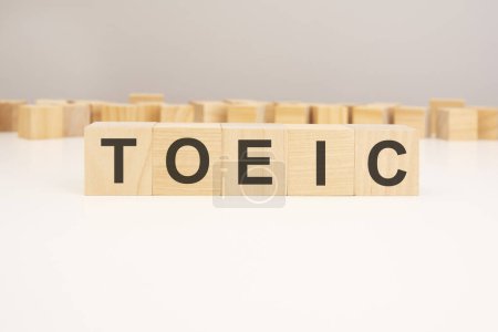 Text TOEIC on wooden blocks on white background. Abbreviation of Test of English for International Communication.