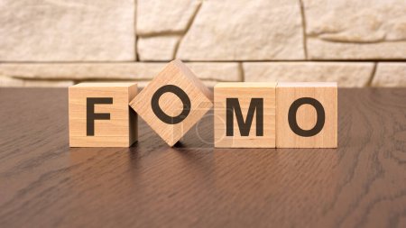 word FOMO cube wood on wooden table background. business concept