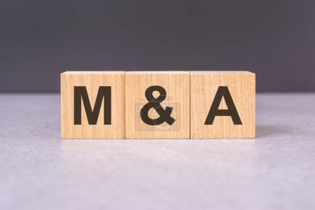 M and A - acronym from wooden blocks with letters, top view on black background