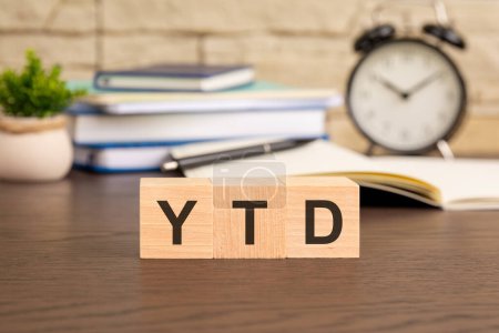 YTD-Symbol. Konzeptwort "YTD - year-to-date" auf Würfeln auf einem schönen Hintergrund aus dem Wecker. Geschäfts- und YTD-Konzept. visuelles Konzept betont die Verfolgung und Bewertung des Geschäftsfortschritts im Laufe des Jahres