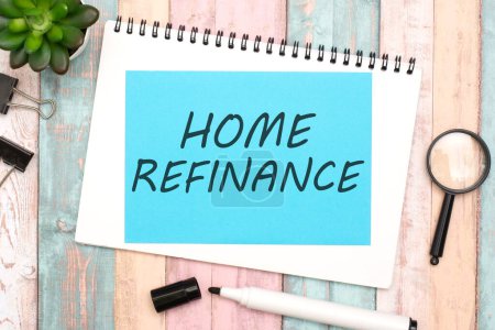text 'HOME REFINANCE' written on a blue sheet of paper with a black marker, placed on a multicolored wooden background, captured from a top view. idea of exploring mortgage refinancing options
