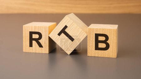 three wooden blocks with the text RTB symbolizes the the of Real-Time Bidding. This concept emphasizes the agility and competitiveness of digital advertising strategies.