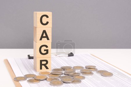 CAGR Wort in Holzklötzen mit Münzen in zunehmenden Stapeln gestapelt. Dieses Konzept unterstreicht die Bedeutung der Bewertung der durchschnittlichen jährlichen Wachstumsrate einer Investition im Laufe der Zeit.