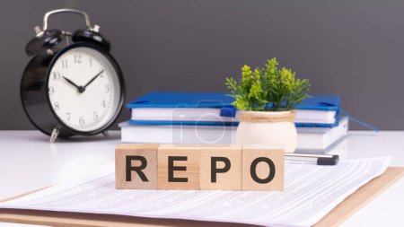 wooden blocks spell out 'REPO' with a small an alarm clock on a gray background, REPO is a financial term that stands for repurchase agreement