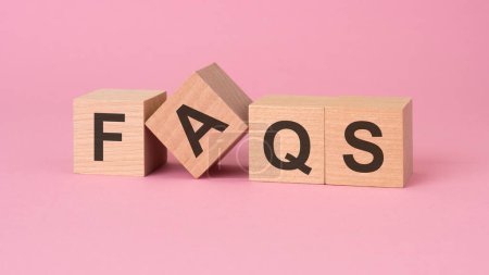 Holzklötze mit FAQs, die auf einer rosafarbenen Oberfläche angeordnet sind, suggerieren einen Fokus auf impliziert Klarheit, Hilfestellung und Anleitung bei gemeinsamen Fragen oder Anliegen.