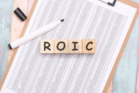 the composition of wooden cubes spelling 'ROIC' on the office table signifies a strategic focus on maximizing profitability and ensuring optimal allocation of resources.