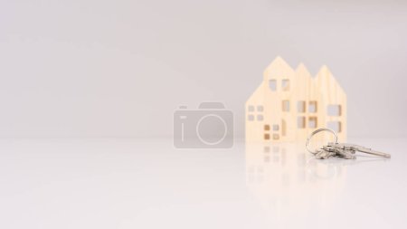 house keys in close-up, with blurred house models in the background and selective focus. conveys a real estate concept