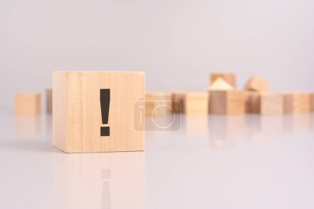 close-up shot of an exclamation mark writing on a wooden block, highlighting urgency and emphasis. background features blank wooden cubes on a gray backdrop, symbolizing potential for personalization
