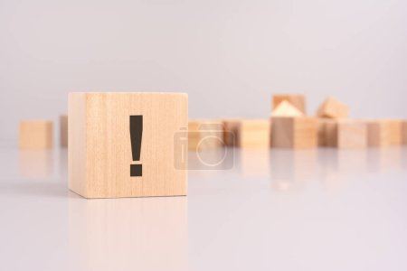 close-up shot of an exclamation mark writing on a wooden block, highlighting urgency and emphasis. background features blank wooden cubes on a gray backdrop, symbolizing potential for personalization