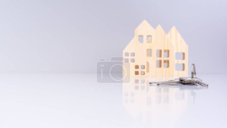 Hausschlüssel in Großaufnahme, mit unscharfen Hausmodellen im Hintergrund und selektivem Fokus. vermittelt ein Immobilienkonzept
