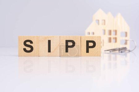 cubes en bois orthographe SIPP accompagné d'une maison modèle et des clés en arrière-plan, indiquant une transaction de location ou un contexte de gestion immobilière. Régime de pension auto-investi