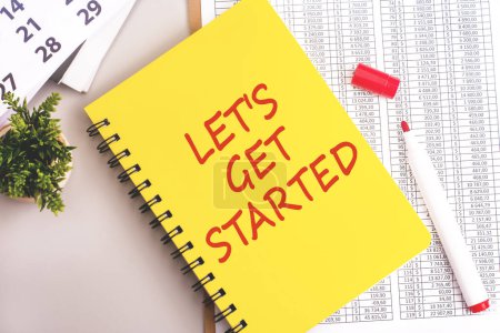 red marker, financial document, white calendar and yellow notebook with 'LET's GET STARTED' text on grey background