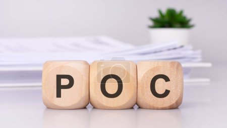 Photo for Wooden cubes spelling out 'POC' on the office table, with a white paper document on the background, poc - short for proof of concept - Royalty Free Image