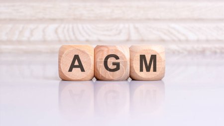 Cartel AGM en la mesa gris con fondo de madera. AGM - abreviatura de Junta General Anual.