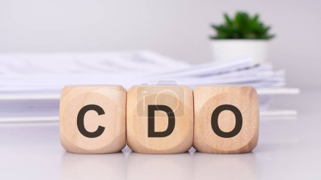 wooden cubes spelling out 'CDO' on the office table, with a white paper document on the background, CDO - short for Collateralized debt obligations