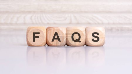 les blocs de bois portant la mention "FAQS" symbolisent l'accent mis sur les questions fréquemment posées et les réponses complètes