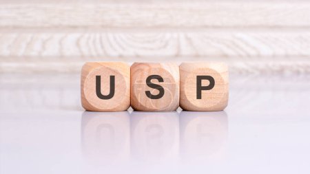 USP-Schild auf dem grauen Tisch mit Holzhintergrund. USP - Abkürzung für Unique Selling Proposition.