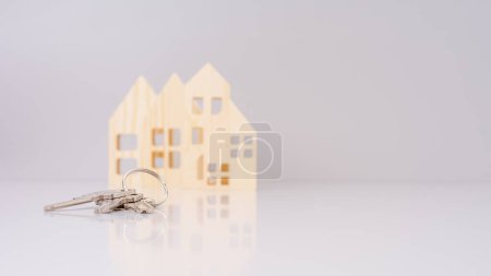 house keys in close-up, with blurred house models in the background and selective focus. conveys a real estate concept