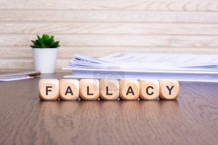 wooden blocks displaying the word 'FALLACY' signify a