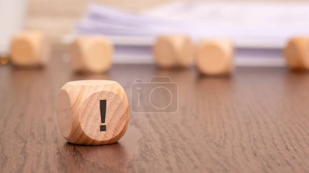 Photo for In the foreground is one wooden cube with a exclamation point. in the background is a row of wooden blocks (out of focus). - Royalty Free Image