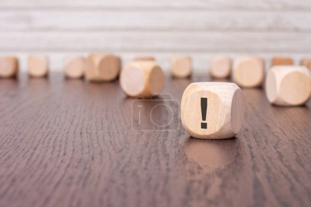 in the foreground is one wooden cube with a exclamation point. in the background is a row of wooden blocks (out of focus).
