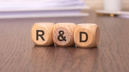 text 'R and D - Research and development' on wooden cubes, brown background