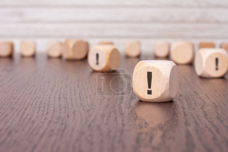 in the foreground is one wooden cube with a exclamation point. in the background is a row of wooden blocks out of focus.