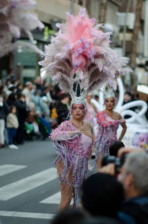 February 20, 2022 - Torrevieja, Spain. Beautiful women in elaborate pink carnival costume with jewels and feathers dance on street during annual Carnival in Spain. Tourism and entertainment.