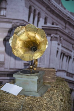 Gramophone vintage au sommet d'une balle de foin, évoquant nostalgie et charme rustique. Espace pour le texte.