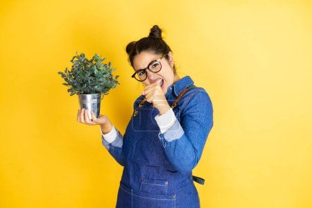 Photo for Young caucasian gardener woman holding a plant isolated on yellow background Punching fist to fight, aggressive and angry attack, threat and violence - Royalty Free Image