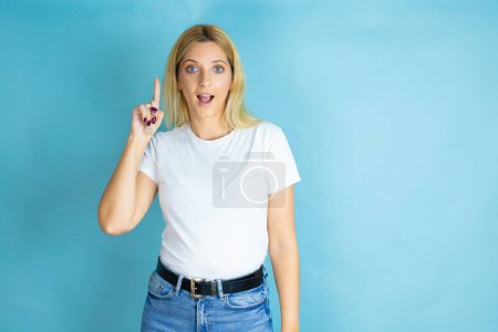 Young beautiful woman wearing casual t-shirt over isolated blue background surprised and thinking with her finger on her head that she has an idea.