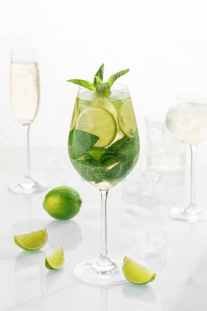Téléchargez les photos : Mohito cocktail classique en verre sur fond blanc avec citron vert, citron, menthe, soda, alcool. - en image libre de droit