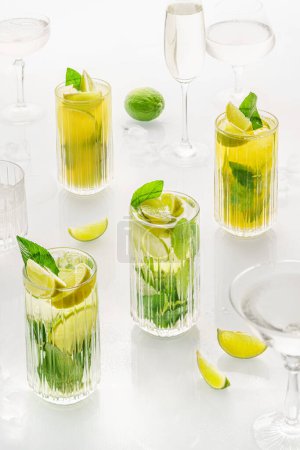Photo for Classic cocktail mix of different lemonades , mohito in glass on white background with lime, lemon, mint, apple ,soda,  alcohol. - Royalty Free Image