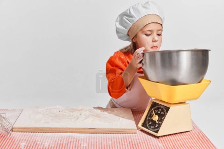 Photo for Cute little child, girl in image of chef cooking over grey background. Measuring flour. Concept of childhood, creativity, retro style, vintage fashion, future profession, friendship, art - Royalty Free Image