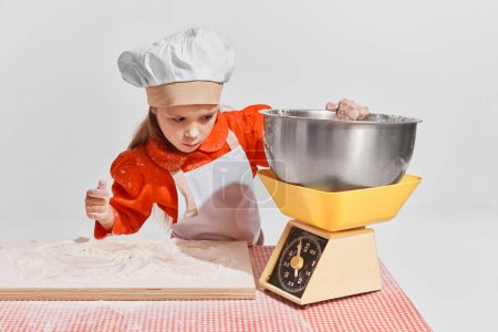 Photo for Cute little child, girl in image of chef cooking over grey background. Measuring flour. Concept of childhood, creativity, retro style, vintage fashion, future profession, friendship, art - Royalty Free Image