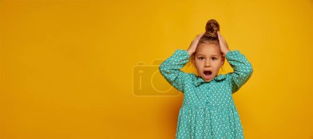 Surprised child. Cute little happy girl, kid with long curly hair looking at camera isolated over yellow background. Concept of children positive emotions, beauty, facial expressions. Copy space for