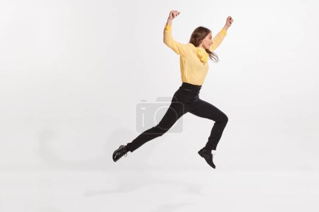 Portrait of young woman jumping, moving forwards isolated over white studio background. Growing professional ambitions. Concept of business, IT profession, occupation, economy, NFT system.