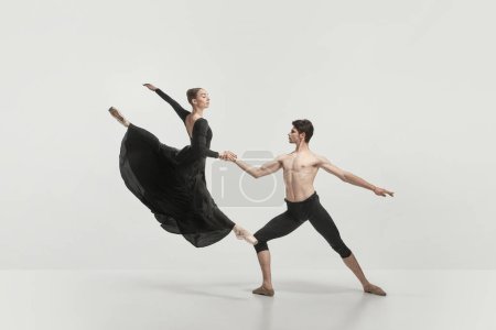Young man and woman, ballet dancers performing isolated over grey studio background. Flying high. Concept of classical dance aesthetics, choreography, art, beauty. Copy space for ad