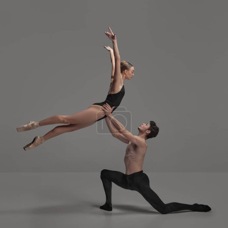 Young man and woman, ballet dancers performing isolated over dark grey studio background. Beautiful tender couple. Concept of classical dance aesthetics, choreography, art, beauty. Copy space for ad