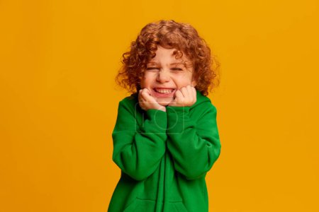 Photo for Portrait of cute little girl, child with curly red hair posing, smiling isolated over yellow background. Concept of childhood, emotions, lifestyle, fashion, happiness. Copy space for ad - Royalty Free Image