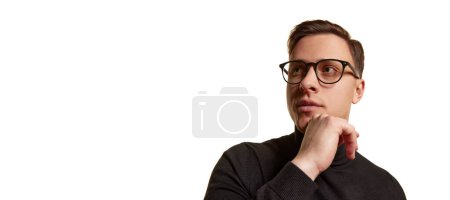 Téléchargez les photos : Portrait de bel homme d'affaires élégant en tenue noire totale portant des lunettes posant isolé sur fond blanc. Concept de beauté, de mode, de style et d'affaires. Ça a l'air sérieux. Dépliant - en image libre de droit