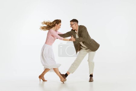 Photo for Two emotional dancers in vintage style clothes dancing swing dance, rock-and-roll isolated on white background. Timeless traditions, 1960s american fashion style and art. Couple look happy, delighted - Royalty Free Image