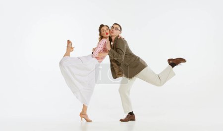 Téléchargez les photos : Deux danseurs émotionnels dans des vêtements de style vintage dansant la danse swing, rock and roll isolé sur fond blanc. Traditions intemporelles, style et art américains des années 1960. Couple air heureux, enchanté - en image libre de droit