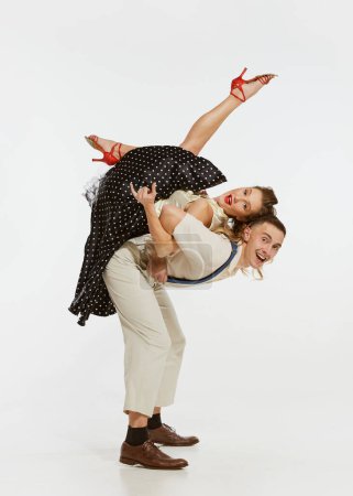 Foto de Bailarines profesionales felices y expresivos en ropa de estilo americano de los años 60 bailando danza rock and roll aislada sobre fondo blanco. Música, energía, felicidad, humor, acción - Imagen libre de derechos