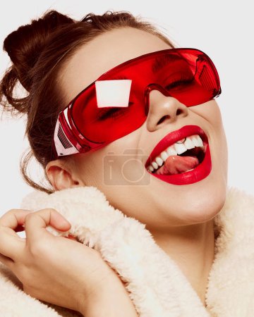 Foto de Retrato de cerca de una joven mujer sonriente con lápiz labial rojo brillante sonriendo sobre fondo blanco. Blanqueamiento dental. ¡Cuidado! Concepto de alta moda, salud, emociones, maquillaje, belleza, estilo revista, anuncio - Imagen libre de derechos