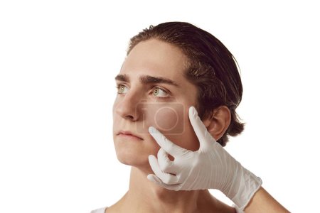 Photo for Portrait of young man and female hands in gloves on male face isolated on white background. Beauty injections. Concept of male beauty, skincare, plastic surgery, cosmetology, health. Copy space for ad - Royalty Free Image