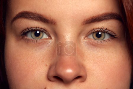 Attentive look. Close-up image of intense green-brown female eyes looking at camera. Concept of vision, contact lenses, eyebrow makeup, health, medical care. Poster, ad