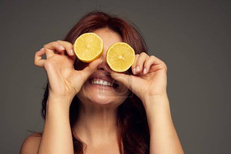 Photo for Portrait of beautiful red-haired woman, smiling, posing with lemons isolated over dark grey background. Vitamins. Concept of beauty, natural cosmetology, hair and face treatment, cosmetics, care. Ad - Royalty Free Image