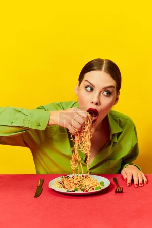 Photo for Emotional young girl eating spaghetti, noodles with hands on red tablecloth over yellow background. Vintage style. Food pop art photography. Complementary colors. Copy space for ad, text - Royalty Free Image