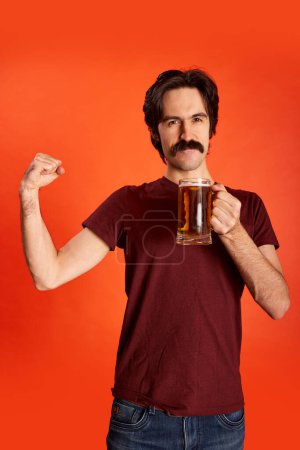Photo for Portrait of emotive man with moustache posing with lager beer mug over red background. Football fan, traditional drink. Concept of emotions, beer degustation, lifestyle, facial expression, Oktoberfest - Royalty Free Image